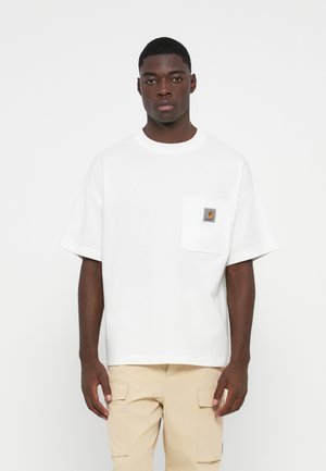 White cotton oversized t-shirt with a round neckline, short sleeves, and a chest pocket featuring a logo patch. Smooth texture, casual design.