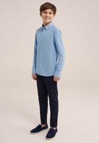 Cămașă albastru deschis cu mâneci lungi, cu nasturi, asortată cu pantaloni negri închis și pantofi slip-on albaștri. Material neted cu un design casual.