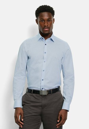 Light blue long-sleeve shirt with dark blue geometric pattern, button-down collar, and matching buttons paired with dark trousers and a belt.