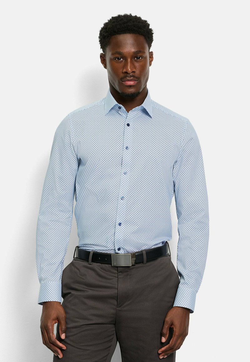 Hellblaues Langarmhemd mit dunkelblauem geometrischem Muster, mit Knopfkragen und passenden Knöpfen, kombiniert mit dunklen Hosen und einem Gürtel.