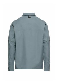 Lyseblå langærmet skjorte med krave, knaplukning ved halsen og enkelt design. Har syninger og manchet detaljer.