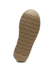 Gummisohle in Hellbraun mit einer strukturierten Oberfläche, die ein wellenförmiges Muster und erhabene, kreisförmige Elemente für besseren Halt aufweist.