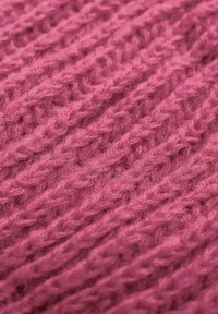 Dziane tkanina w intensywnym różu, z wyraźnym wzorem o teksturowanej fakturze, z przeplatanymi nićmi oraz miękkim, puszystym wyglądem.