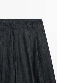 Dark denim trousers with a straight-leg design, prominent crease lines, and stitched waistband detailing. Smooth texture, classic five-pocket style.