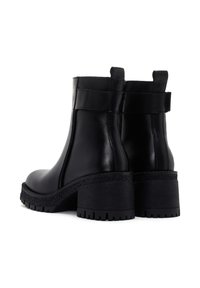 Botas negras de cuero hasta el tobillo con puntera redondeada, paneles laterales elásticos y un tacón grueso y texturizado. Diseño minimalista y acabado suave.