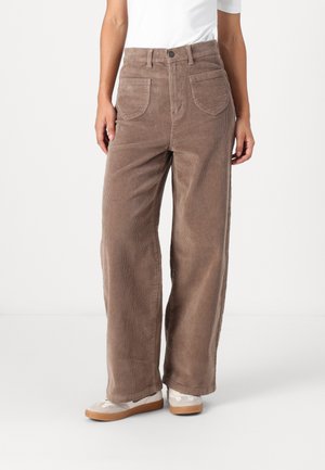 Brown corduroy wide-leg pants with two front pockets, textured fabric, high waist, and a button closure. Worn with casual shoes.