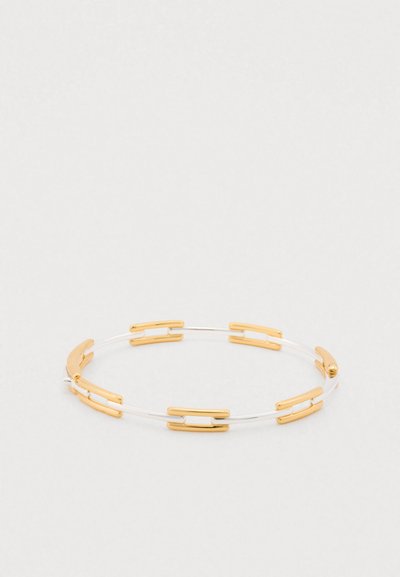 Gold and clear acrylic bangle bracelet featuring alternating gold links and clear sections, circular shape with smooth texture.