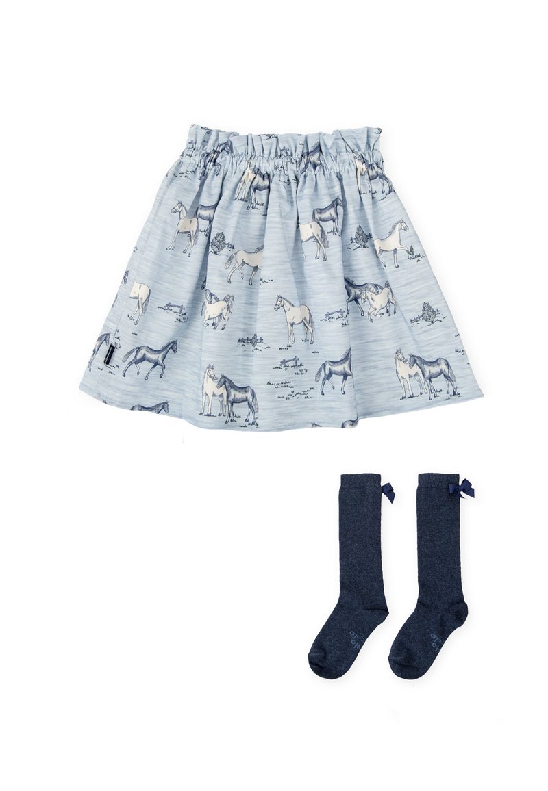 Jupe bleu clair avec des motifs de chevaux, taille froncée ; associée à des chaussettes jusqu'aux genoux navy avec de petits nœuds en haut.