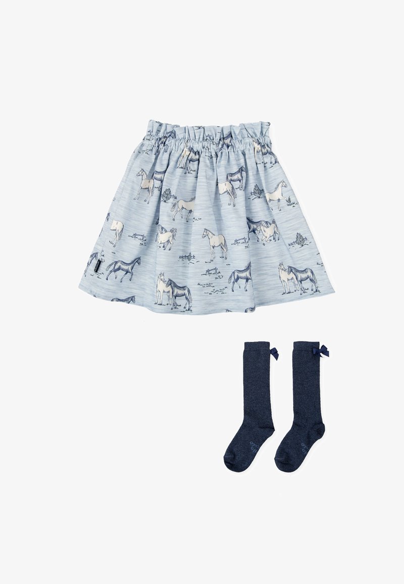 Falda de color azul claro con patrones de caballos, cintura fruncida; combinada con medias altas de color marino que tienen pequeñas lazadas en la parte superior.