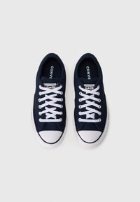Baskets en toile bleu marine avec embout en caoutchouc blanc, lacets blancs et semelle noire. Logo "Converse All Star" sur la languette.