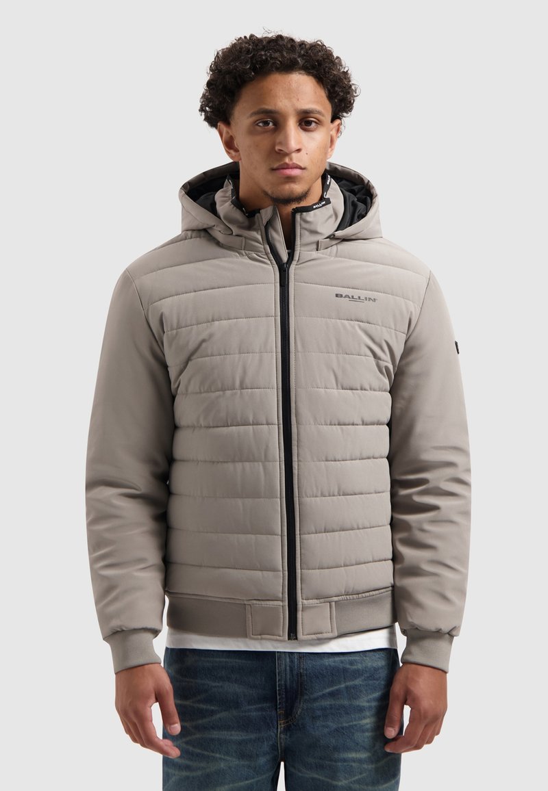 Lichtgrijze gewatteerde jack met een ritssluiting en capuchon. Heeft ribgebreide manchetten en zoom met zwarte accenten, een getextureerd oppervlak en logo-detail.