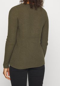 Strickpullover in dunkelolivgrün, mit enganliegendem Design, langen Ärmeln, gerippter Textur und leichtem High-Low-Saum.