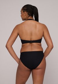 Zwart geribbelde bikini set met een halternek top met achterste sluiting en bijpassende hoge taille onderbroek, die een gestructureerd ontwerp laat zien.