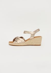 Metallic gold espadrille wedge sandals with a knotted design, textured fabric straps, and a jute-wrapped midsole.