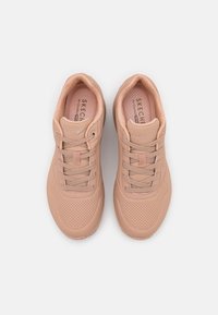 Ljusrosa Skechers-sneakers med perforerat mönster, tygöglor och platta snören. Vadderad krage och texturerad innersula.