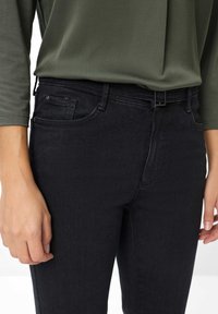 Jeans in denim nero con una vestibilità slim, dotati di zip sul davanti, passanti per cintura e tasche anteriori. Il materiale ha una leggera elasticità per garantire comfort.