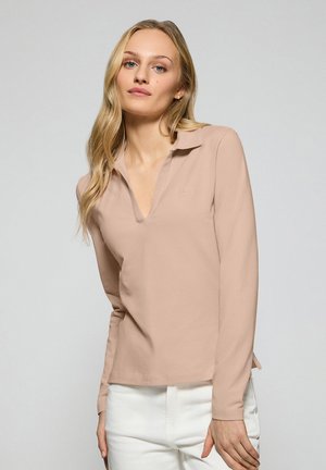 Lange mouw polo-shirt van zacht beige stof met een v-hals ontwerp en subtiele logo-details, gecombineerd met witte broeken. Soepele textuur.