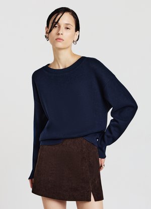 Maglione blu navy a maglia con ampio scollo a girocollo e spalle abbassate, abbinato a una minigonna in velluto a coste marrone con spacco laterale.