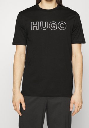 Sort bomulds-T-shirt med hvid kontrastomrids af ordet "HUGO" trykt henover brystet, korte ærmer og almindelig pasform.