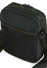 Bolso cruzado negro con dos compartimentos con cremallera, que presenta un frente de malla texturizada y correa ajustable. Fabricado con tela duradera.