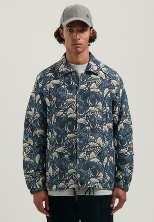 Floral patterned jacket in dark blue and ivory, made of textured fabric, featuring a collared neckline and elasticized cuffs.