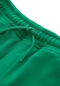 Groene katoenen shorts met een elastische tailleband, voorzien van een trekkoordsluiting en een zachte textuur. Geen extra patronen of accenten aanwezig.