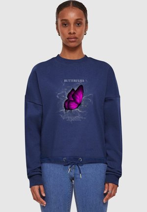 Tummansinisessä hupparissa on violetista ja valkoisesta tekstiä sisältävä perhosgrafiikka. Huppari sisältää naruhelmuksen ja ribattuina hihansuut. Pehmeää puuvillakangasta.