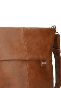 Borsa a tracolla in pelle marrone con una texture liscia, flap pieghevole, tracolla regolabile e un piccolo cartellino con marchio.