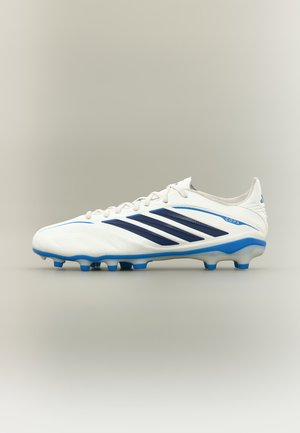 Λευκά και μπλε ποδοσφαιρικά παπούτσια Adidas Copa με μαύρες ρίγες και μπλε τάπες σε ουδέτερο φόντο.