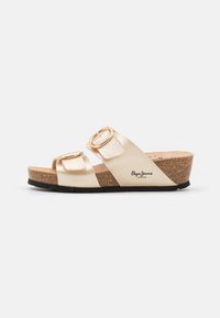 Sandali con zeppa color oro, dotati di due cinghie regolabili con fibbie circolari, plantare in sughero e suola in gomma nera. Logo del marchio sul lato.