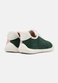 Baskets en suede vert avec semelles blanches, présentant des accents roses au niveau du talon. Vue de l'arrière avec les lacets visibles.