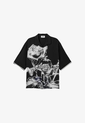 Musta lyhythihainen nappipaita, jossa on rohkea valkoinen, pikselöity kukkakuvio ja hihansuissa hillitty raidallinen reunus.