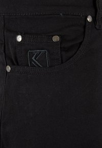 Svarta denimbyxor med en framficka med en broderad logotyp, silverfärgade detaljer och en slät, texturerad tygfinish.
