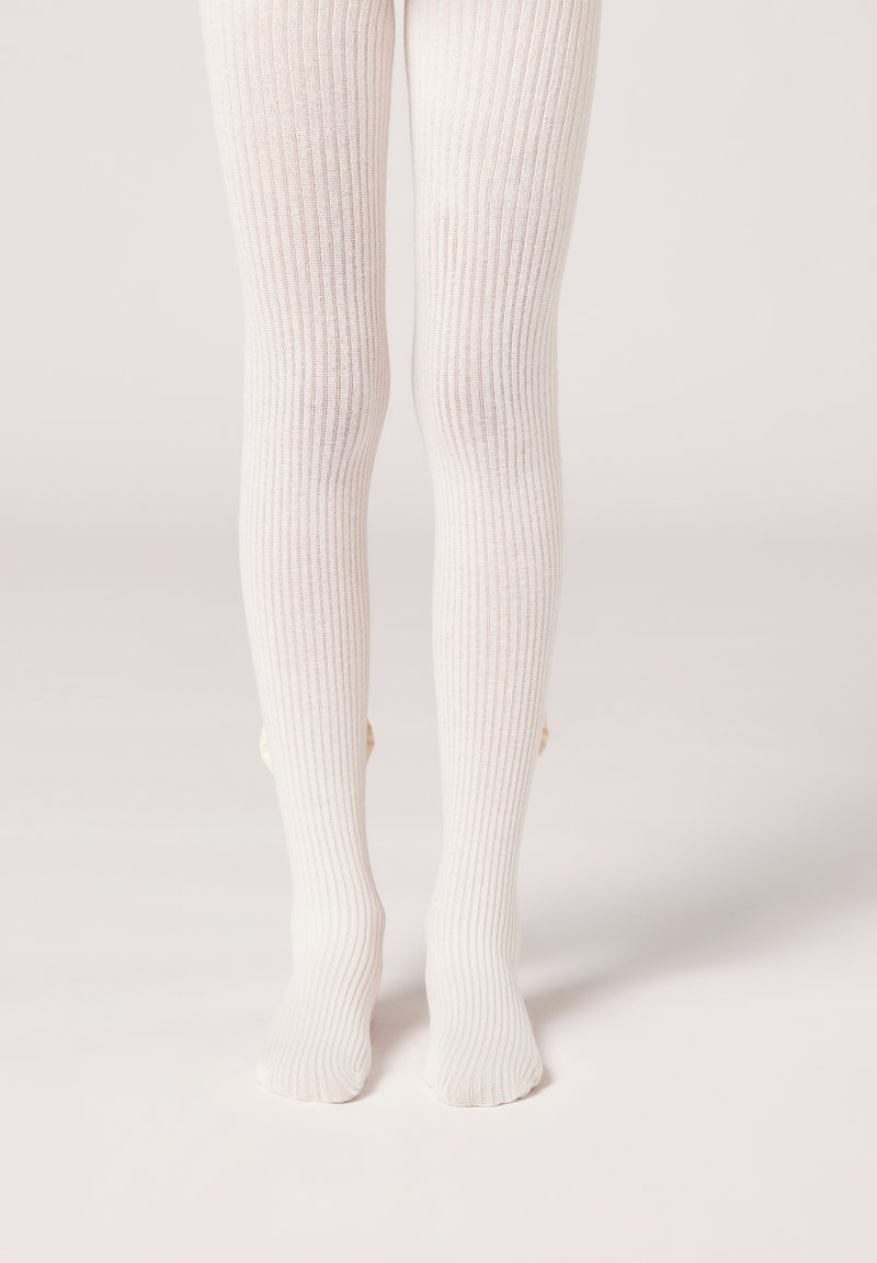 Weiße gerippte Strumpfhosen mit einer weichen Textur, die ein nahtloses Design aufweisen und mit kleinen dekorativen Akzenten in der Nähe der Knöchel versehen sind.