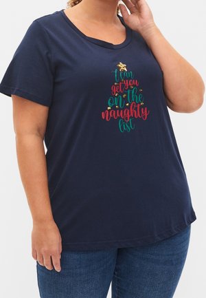 Frau trägt ein marineblaues T-Shirt mit Weihnachtsbaum-Textdesign, auf dem steht "Ich kann dich auf die Liste der Unartigen setzen" und einer goldenen Sternverzierung.