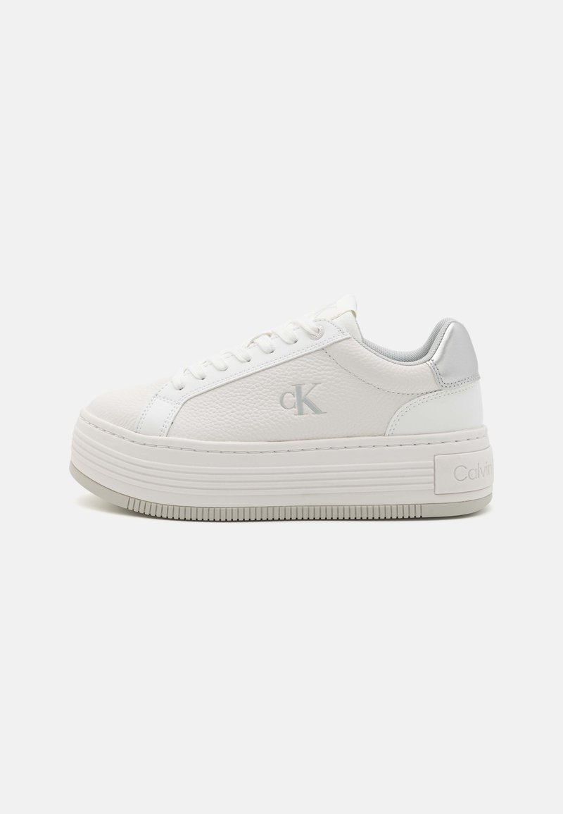 Hvit plattform sneakers med en strukturert overflate, med en sølvfarge akcent og snøring, samt en Calvin Klein-logo på siden. Gummisåle.