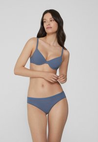 Sada podprsenky a kalhotek v slatové modré barvě, vyrobená z měkkého materiálu. Podprsenka má tvarované košíčky a nastavitelné ramínka; kalhotky mají jednoduchý design.