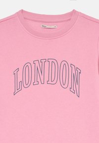 Różowa bluza z okrągłym dekoltem i ribbowymi mankietami. Z przodu znajduje się napis "LONDON" w ciemnoniebieskim kolorze na szerokości klatki piersiowej. Miękka tekstura.