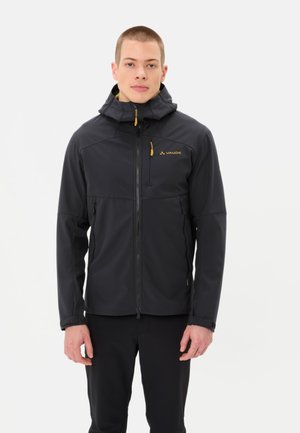 Schwarze Softshelljacke mit Kapuze, ausgestattet mit gelben Reißverschlüssen und Logo. Sie hat eine taillierte Passform, Reißverschlusstaschen und elastisches Material.