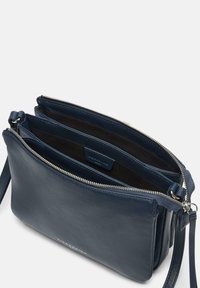 Borsa a tracolla in pelle blu navy con chiusura a zip, due scomparti principali e una texture morbida. Presenta una lunga tracolla regolabile e una marcatura discreta.