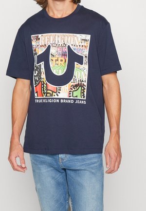 Camiseta de algodón azul marino con un gran estampado gráfico que incluye texto colorido, formas y un logo en la parte frontal, mangas cortas y cuello redondo.