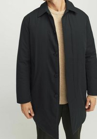 Černý kabát na knoflíky s plochým límcem, dlouhými rukávy a rovný střih. Vyroben z hladkého materiálu, s minimalistickým designem a bez viditelného vzoru.