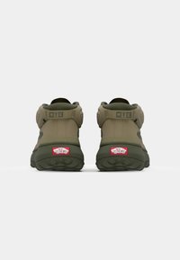 Grønne MTE-sneakers med en teksturert overdel, polstret krage og gummisåle. Inkluderer Vans-logo i rødt på hælen.
