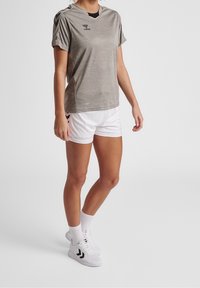 Maglietta sportiva grigia con scollatura a V e maniche corte, abbinata a pantaloni corti bianchi. Presenta un logo sul petto e bordi a righe sui pantaloni.