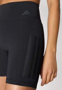 Czarne sportowe szorty z wysokim stanem, o gładkiej fakturze, z boczną kieszenią i trzema poziomymi czarnymi paskami po boku.