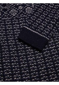 Pull en maille marine présentant un motif texturé avec des accents crème. Les poignets côtelés ajoutent de la structure. Tissu doux de poids moyen.