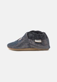 Mørkeblå tekstilslipper med en myk tekstur, elastisk ankel og en beige skinnsåle. Har en liten etikett på siden med "Robeez."