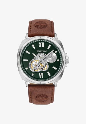 Automatinis laikrodis su tamsiai žaliu ciferblatu, sidabriniu korpusu, rudžiomis odinėmis apyrankėmis ir atviru mechanizmo detalių vaizdu. Yra dideli romėniški skaitmenys XII ir VI.