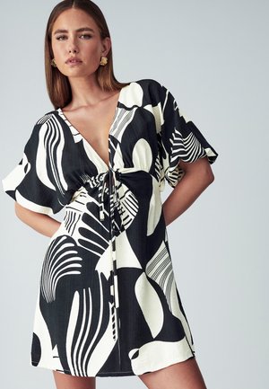 Black and white dress featuring abstract patterns, short sleeves, V-neckline, and a drawstring waist for adjustable fit. Smooth, lightweight fabric.