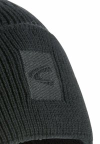Zwarte gebreide beanie met ribbelstructuur en een rechthoekig logo-patch in dezelfde kleur, die een naadloos ontwerp en een zachte afwerking toont.